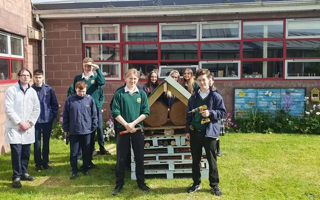 Secondary school students with the bug hotel they built